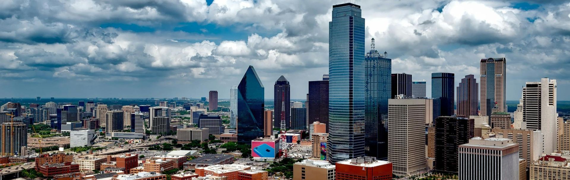 A stunning panoramic view of the Dallas skyline under dramatic clouds, capturing the city's iconic skyscrapers.
