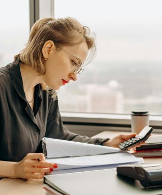 Woman accountant calculating financial documents at office desk.
