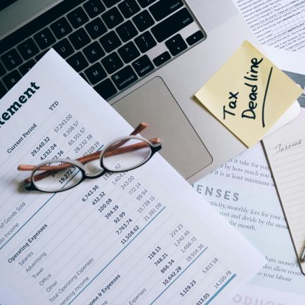 Workspace with laptop, documents, and tax deadline note for financial management.